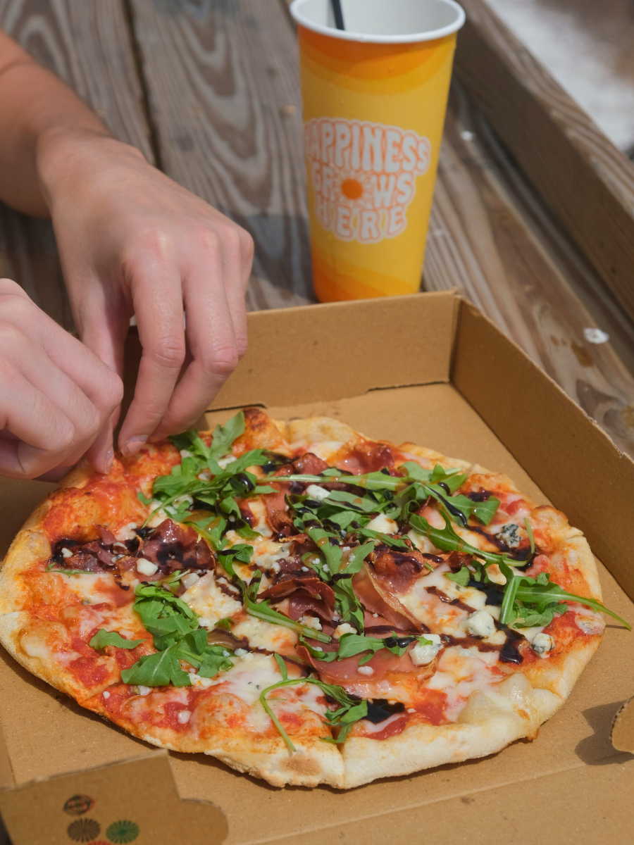 Woman takes a slice of pizza from Harvest Crust pizzeria